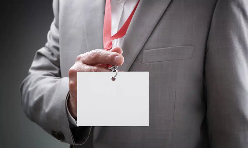 Businessman,At,An,Exhibition,Or,Conference,Showing,A,Blank,Security Businessman at an exhibition or conference showing a blank security identity name card on a lanyard