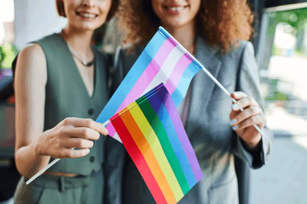 A closeup of two coworkers holding pride flags, demonstrating allyship in the workplace.
