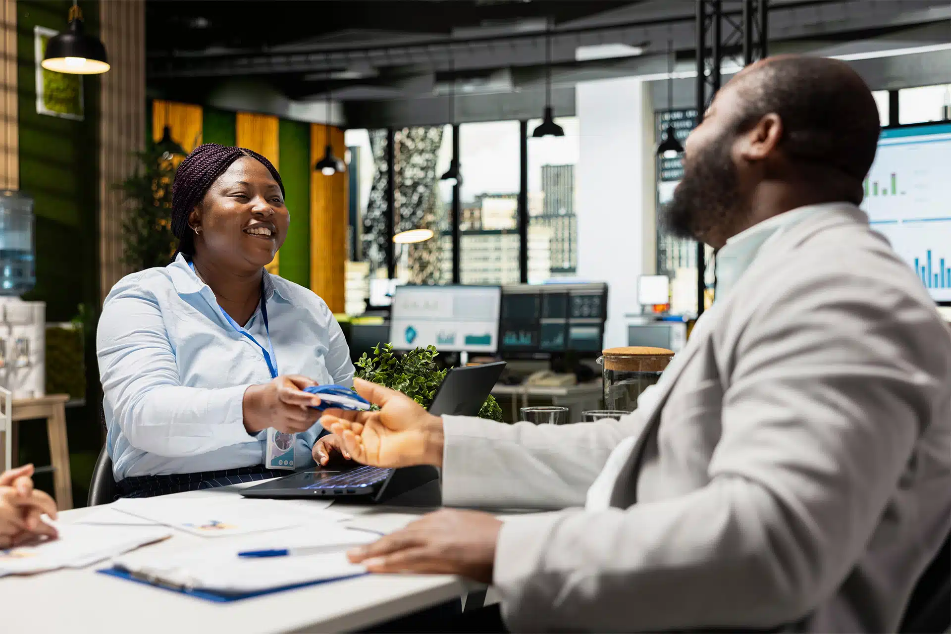 A Crash Course on Employee Identification: Benefits, Uses and Best Practices 4 a HR manager giving an employee identification card to a new hire to wear on a lanyard